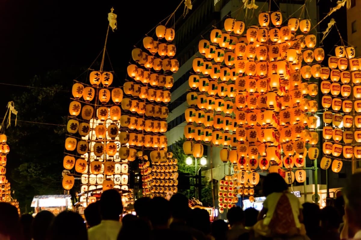 Towering kanto poles strung with hundreds of glowing lanterns rising over the crowd at night on Kanto Oodori in Akita