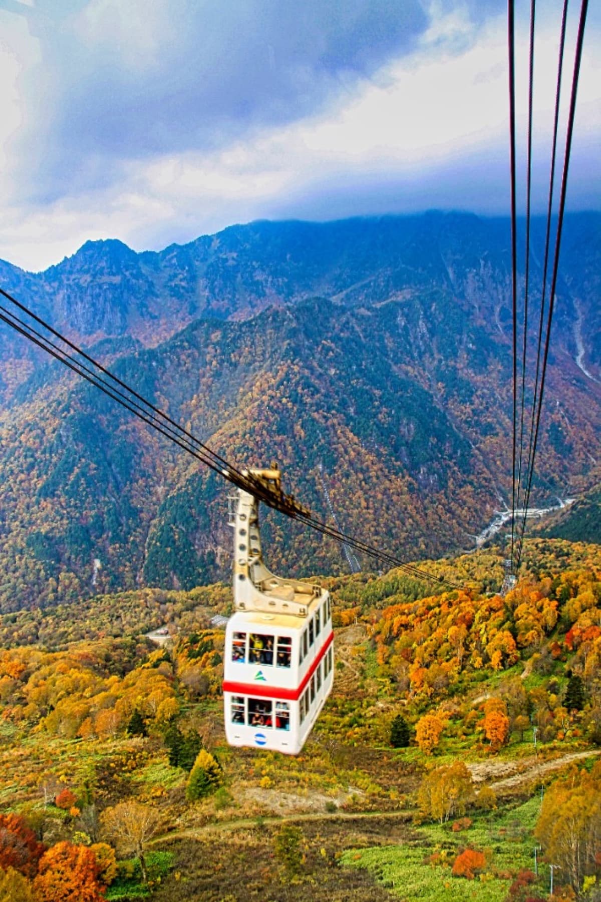 The Shinhotaka Ropeway double-decker gondola crossing a valley of autumn foliage in the Japanese Alps