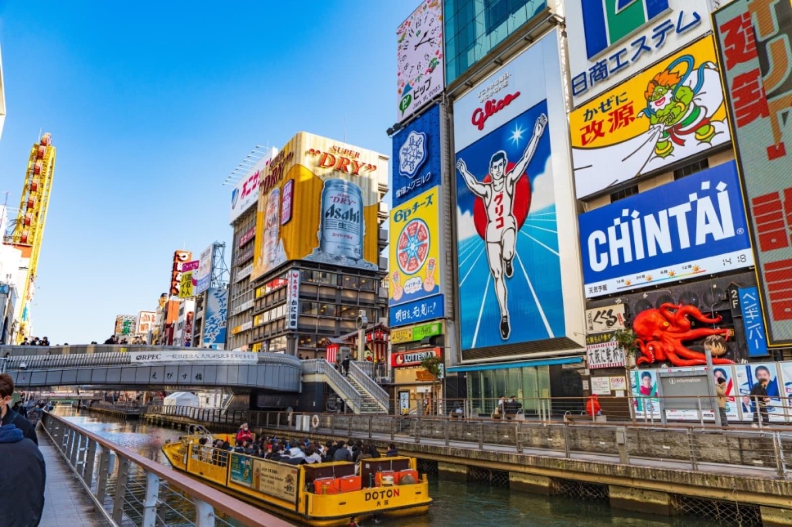 Der Dotonbori-Kanal in Osaka mit dem Glico-Schild und einem gelben Ausflugsboot