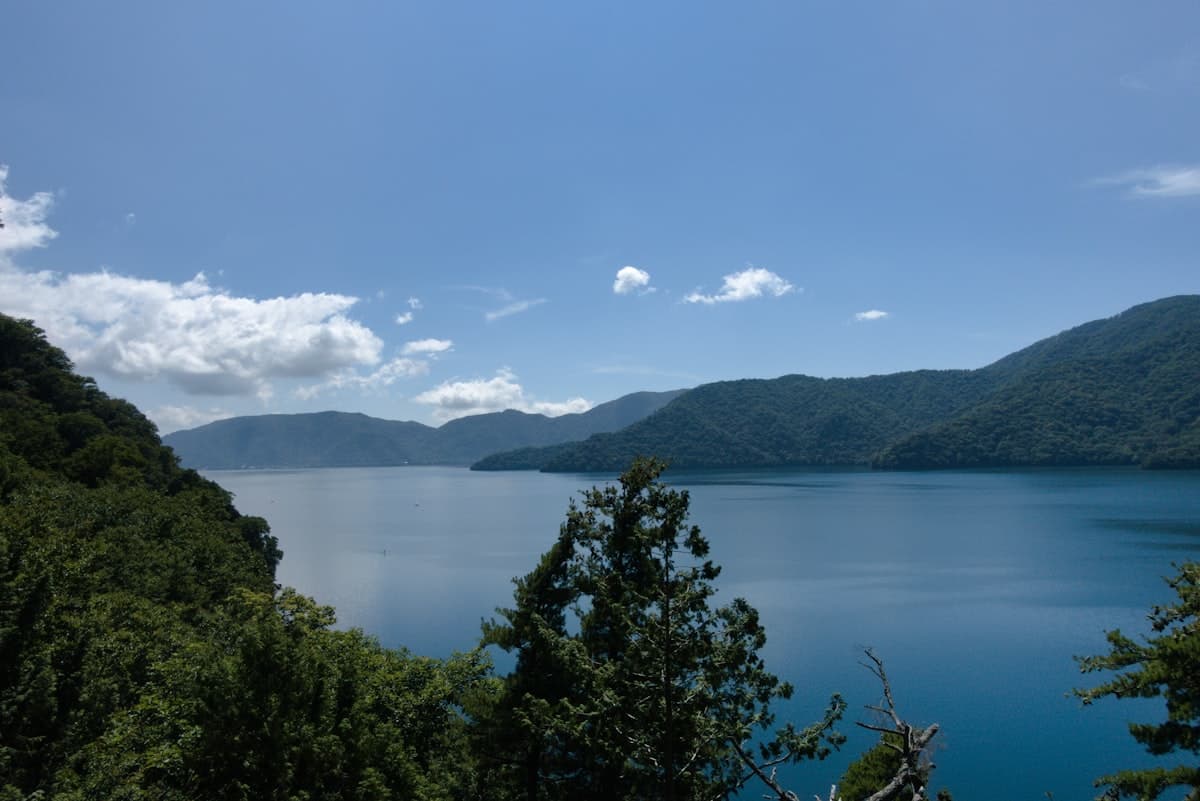 Ein ruhiger blauer See, umgeben von sattgrünen Bergen im Norden Japans