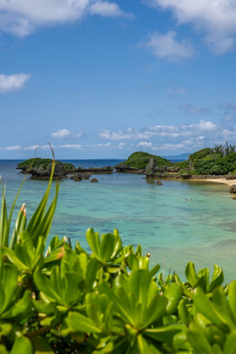 Eine türkisfarbene Bucht mit Sandstrand auf Okinawa unter klarem Sommerhimmel