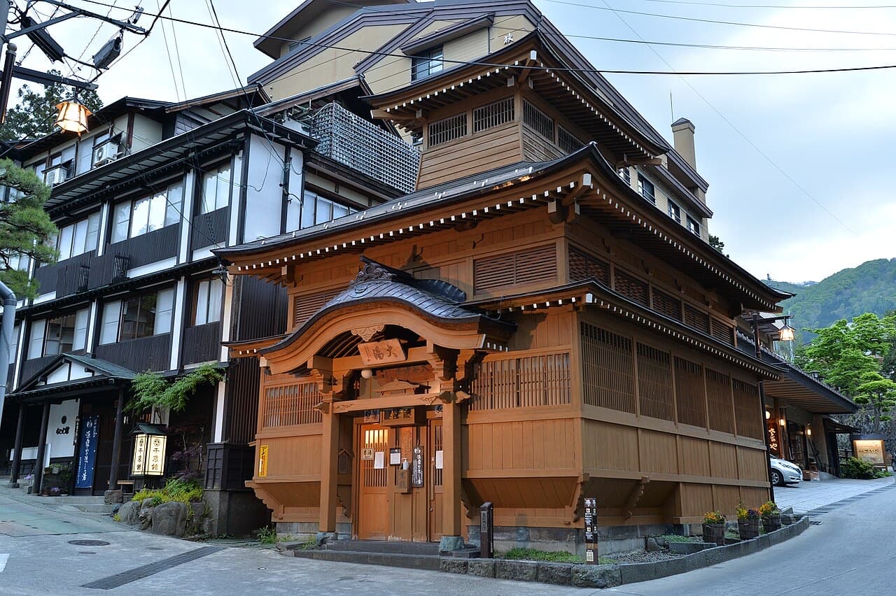 The wooden Oyu public bathhouse with its tiered roof on a street in Nozawa Onsen