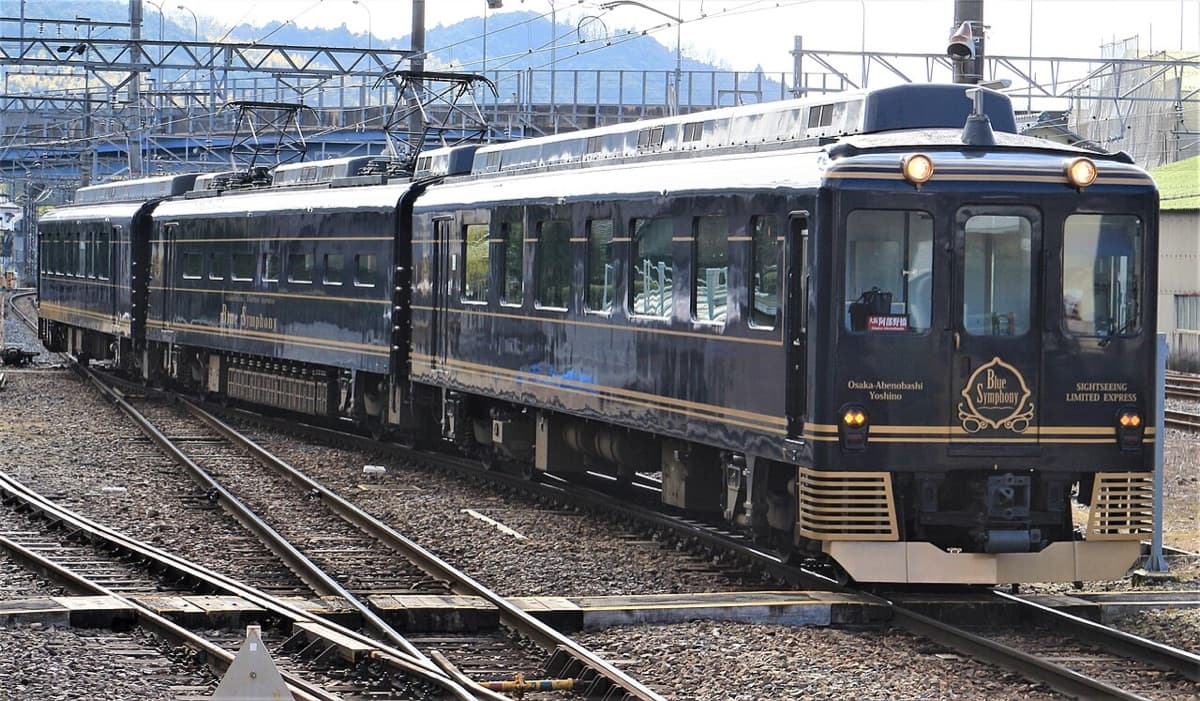 Kintetsu's navy-blue Blue Symphony train with gold lettering standing in a railway yard