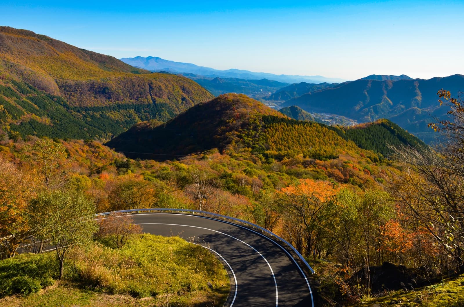 A hairpin curve of the Irohazaka road winding down through autumn-coloured Nikko mountains