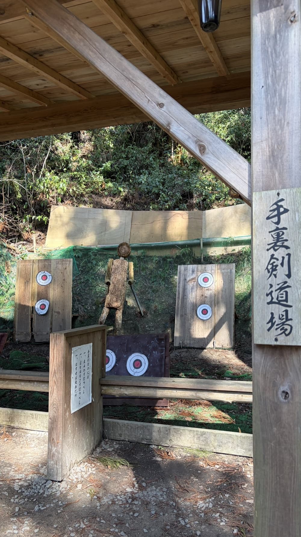 Wooden shuriken-throwing targets and a straw figure under the roofed dojo at Akame 48 Waterfalls