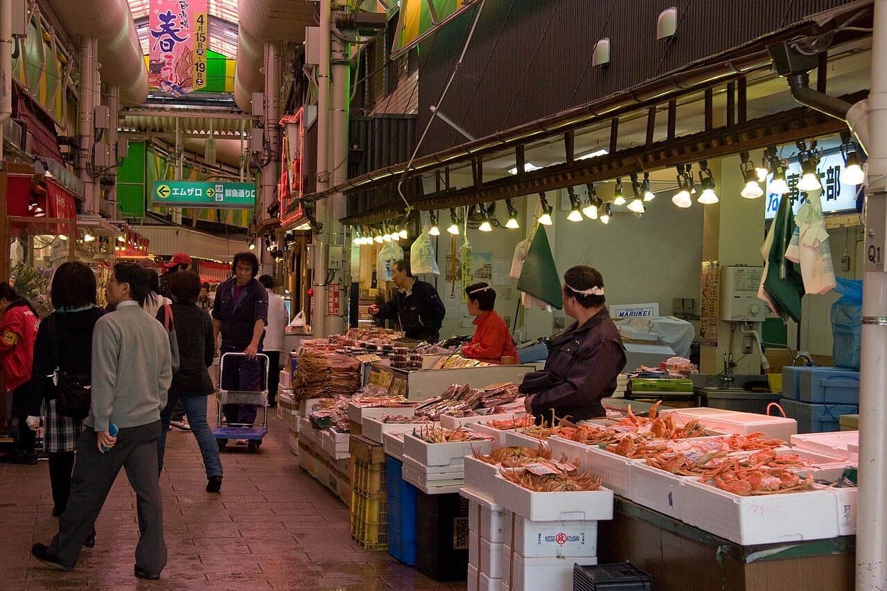 Market stalls piled with crab and seafood under the covered roof of Omicho Market