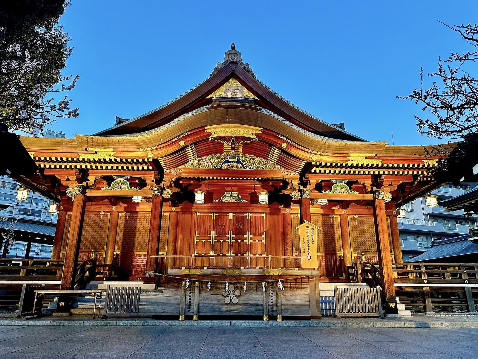 The ornate main hall of Yushima Tenjin shrine in Tokyo under a clear blue sky