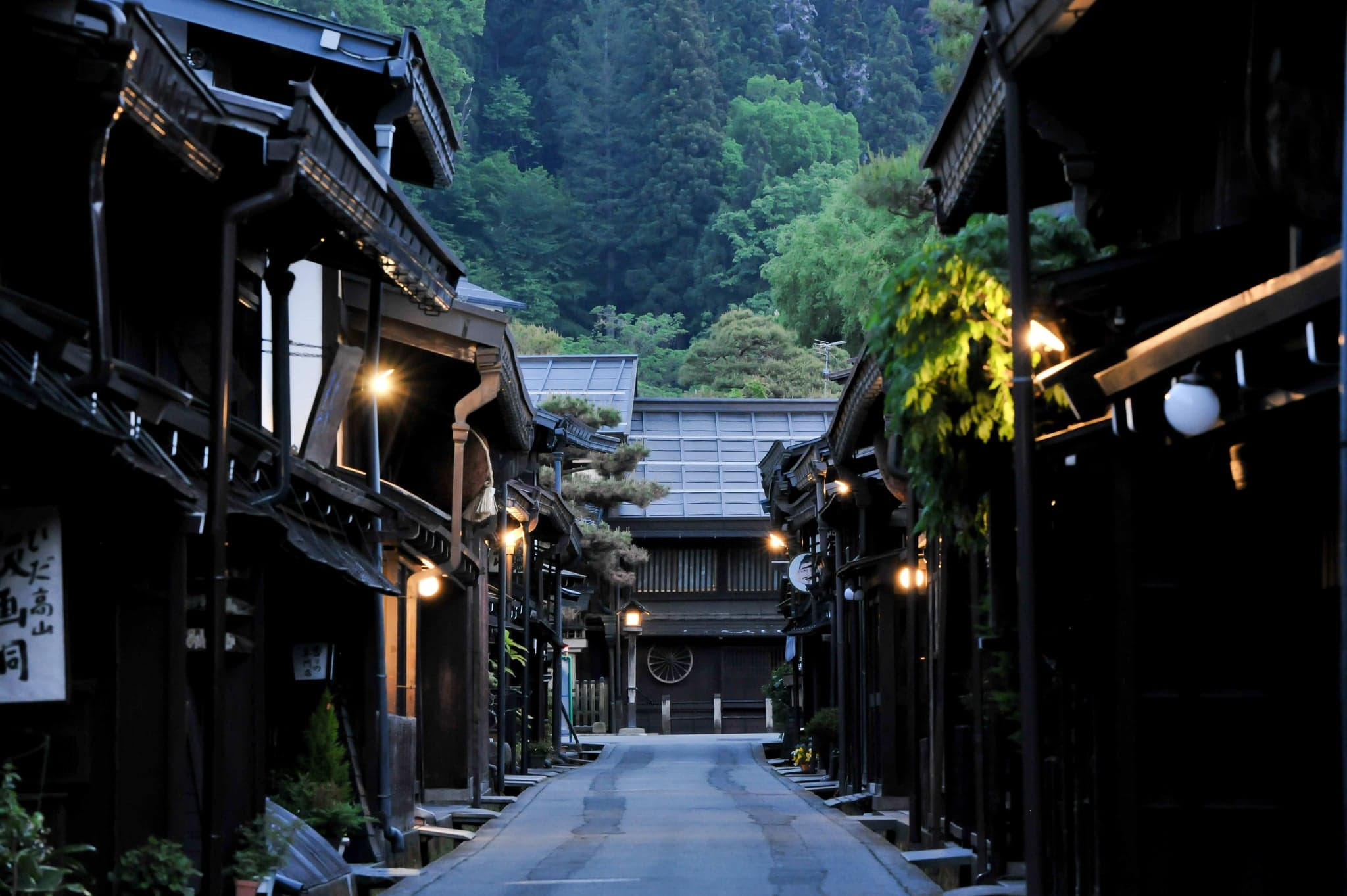Takayama's preserved old town street at dusk with wooden merchant houses and lanterns