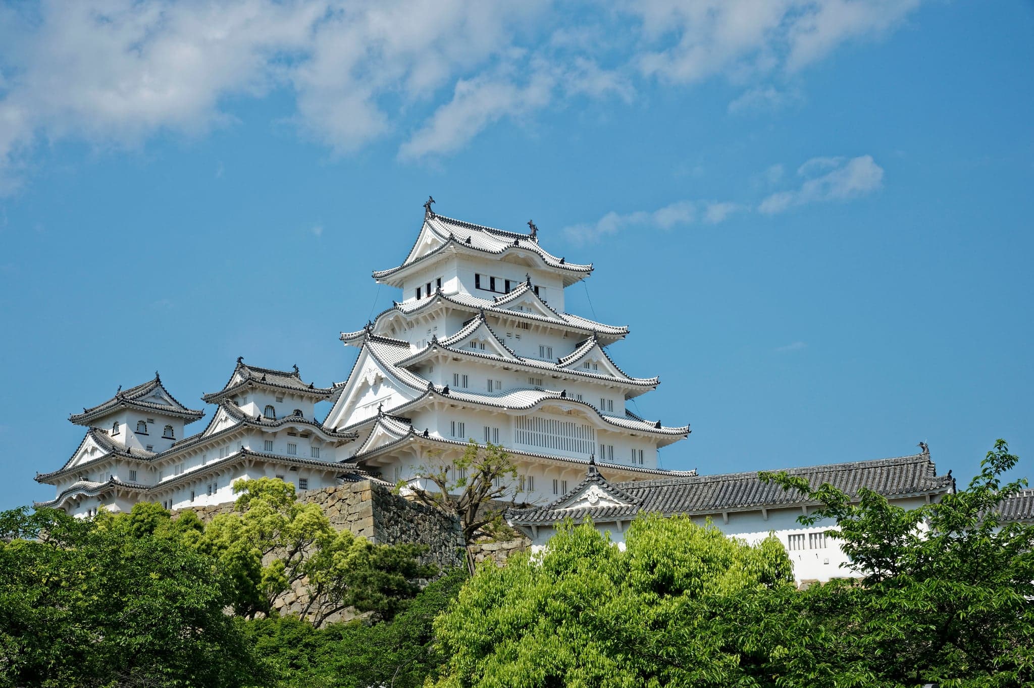 Himeji Castle's white main keep against a blue sky in early summer