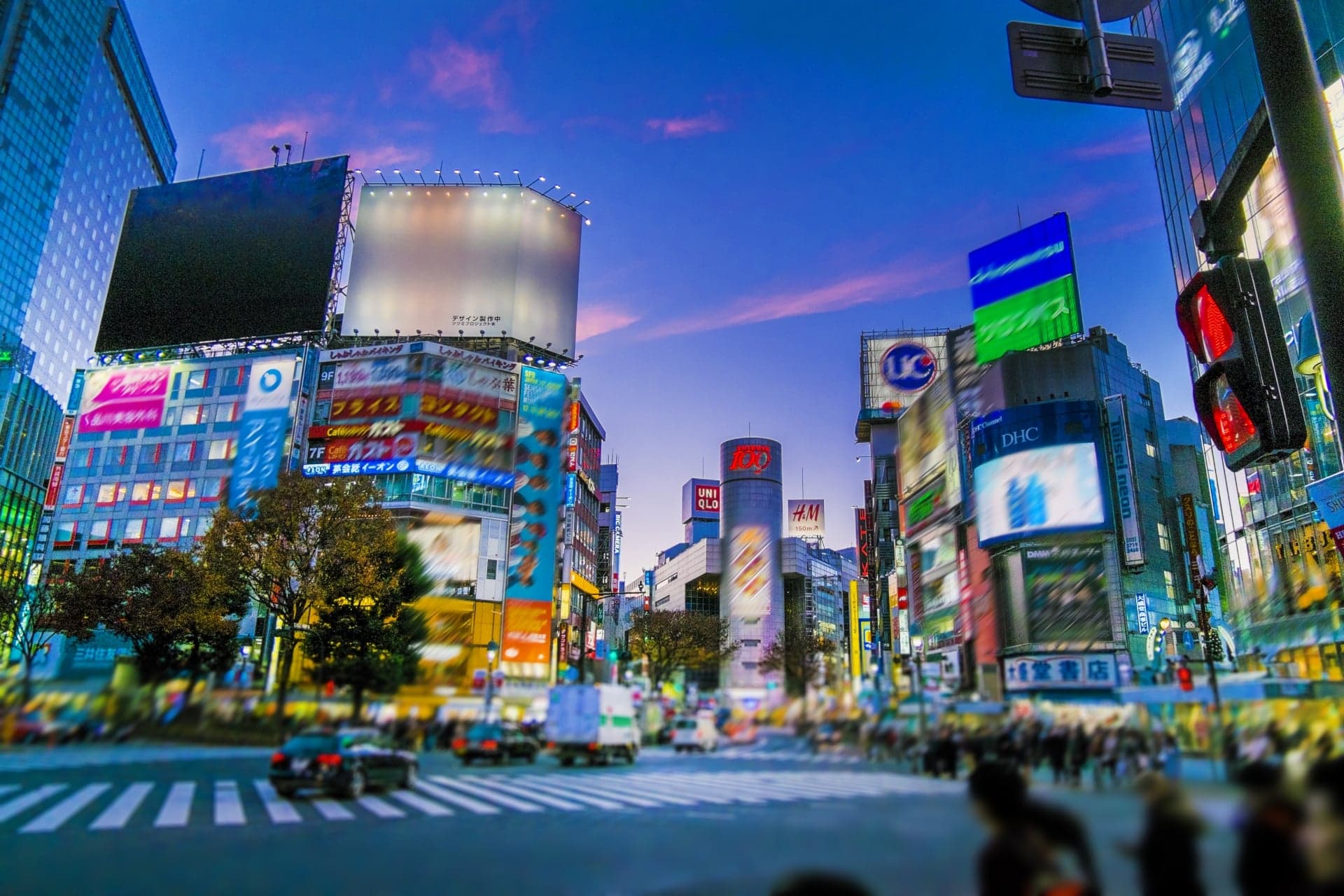 Shibuya Crossing at dusk with the lights of the surrounding buildings coming on