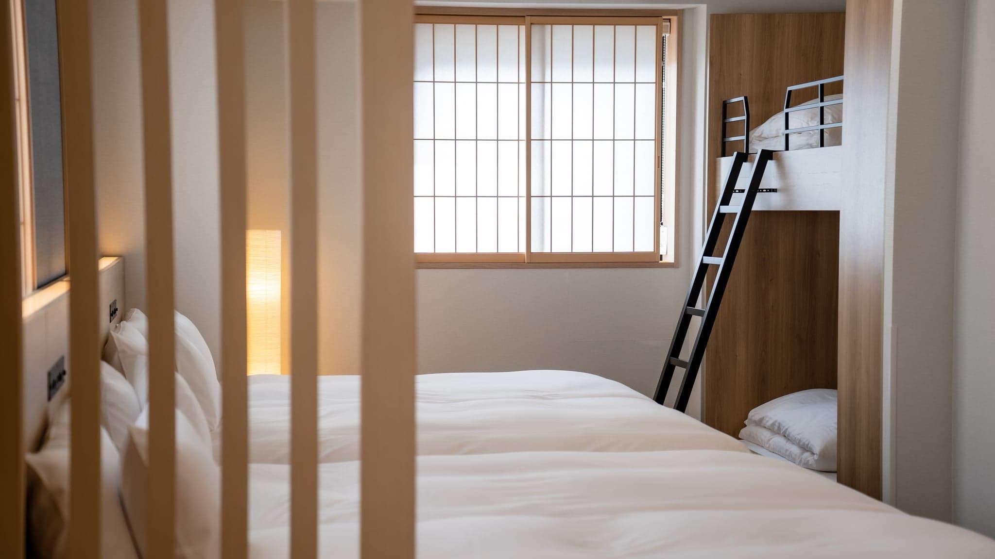 A family room at a MIMARU apartment hotel with a double bed and a wooden bunk bed with a ladder