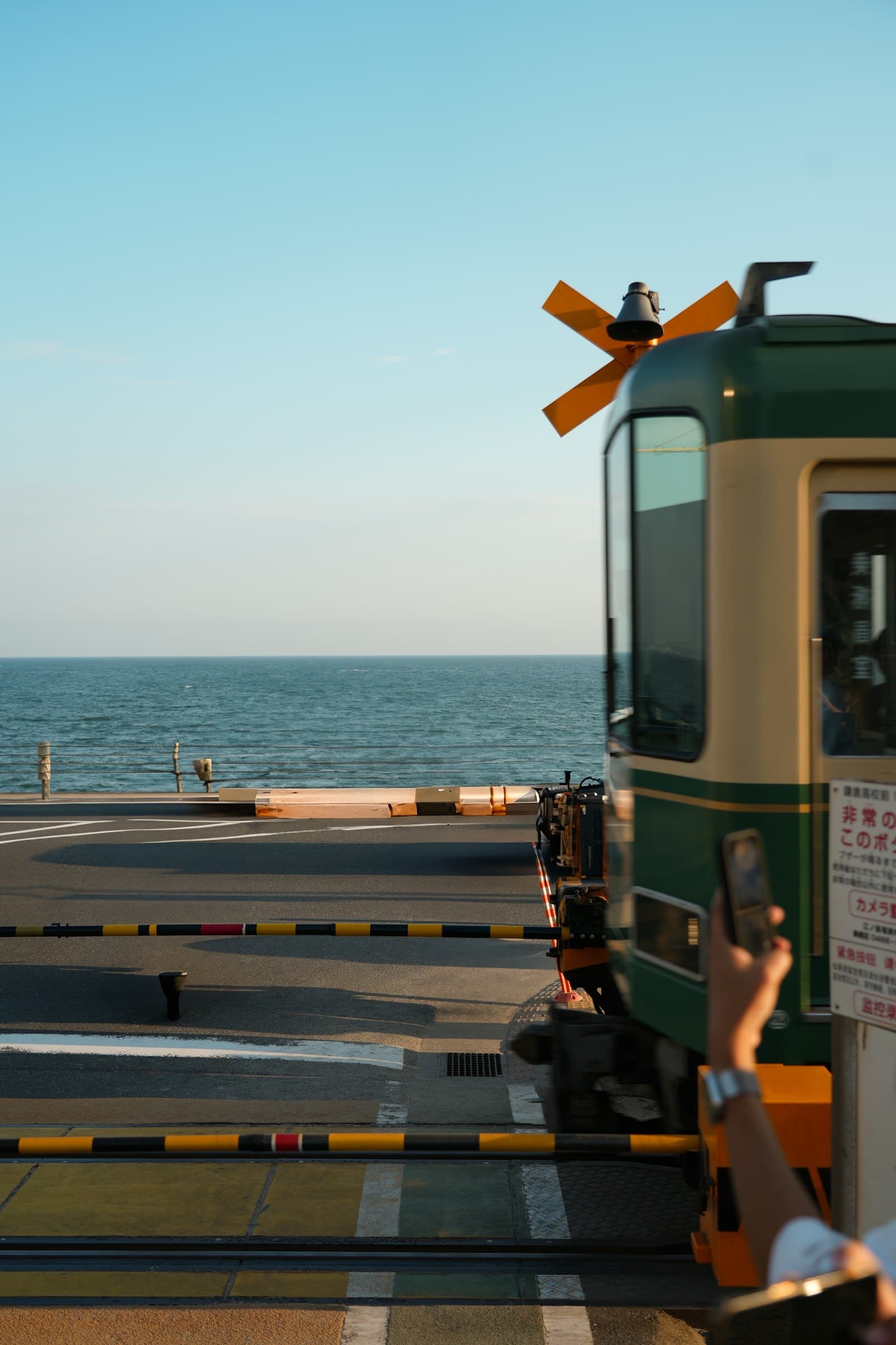 The Enoden train passing the Kamakurakokomae crossing with the Pacific Ocean in the background