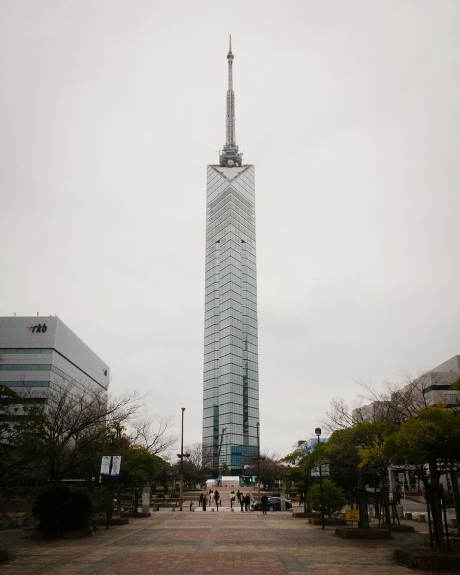 Fukuoka Tower rising at the end of a tree-lined promenade on an overcast day