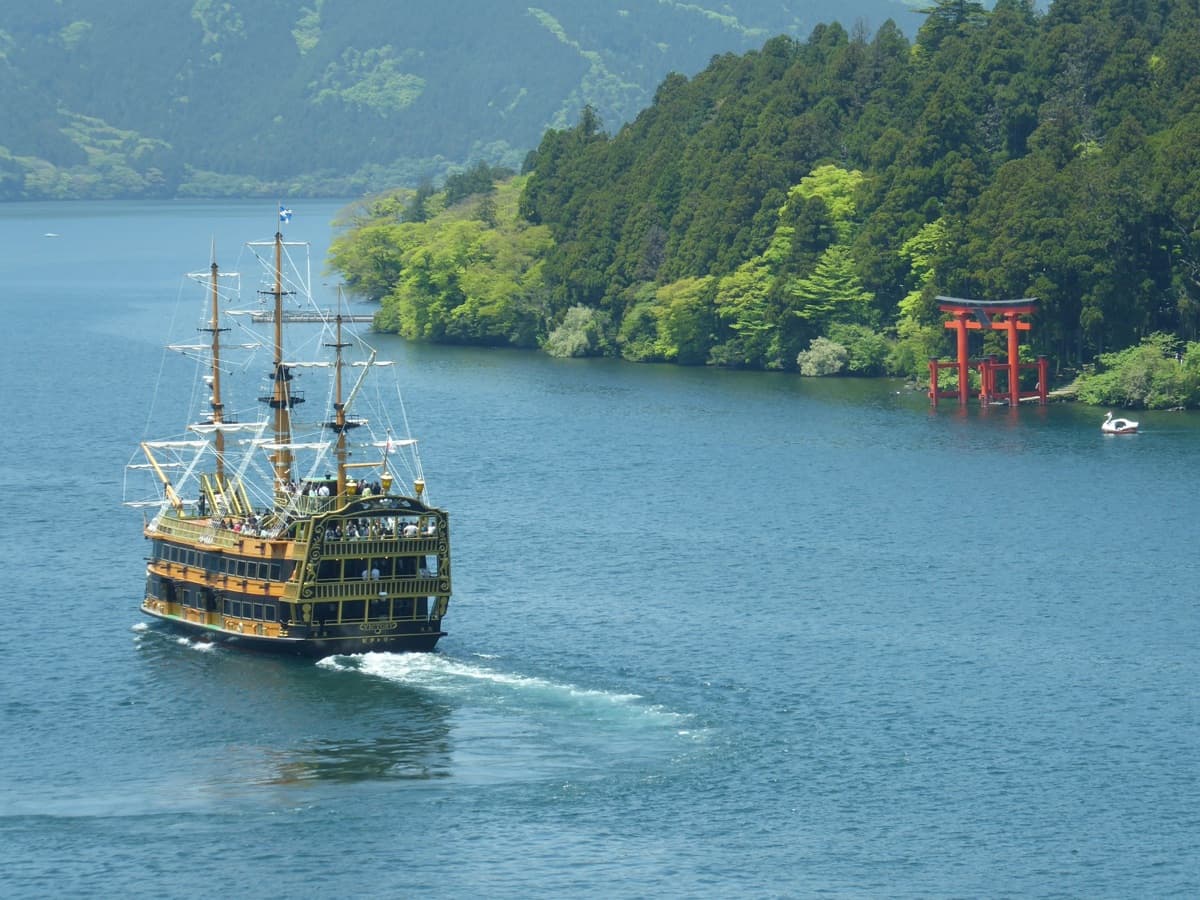 A pirate-style sightseeing ship crossing Lake Ashi toward the red torii of Hakone Shrine