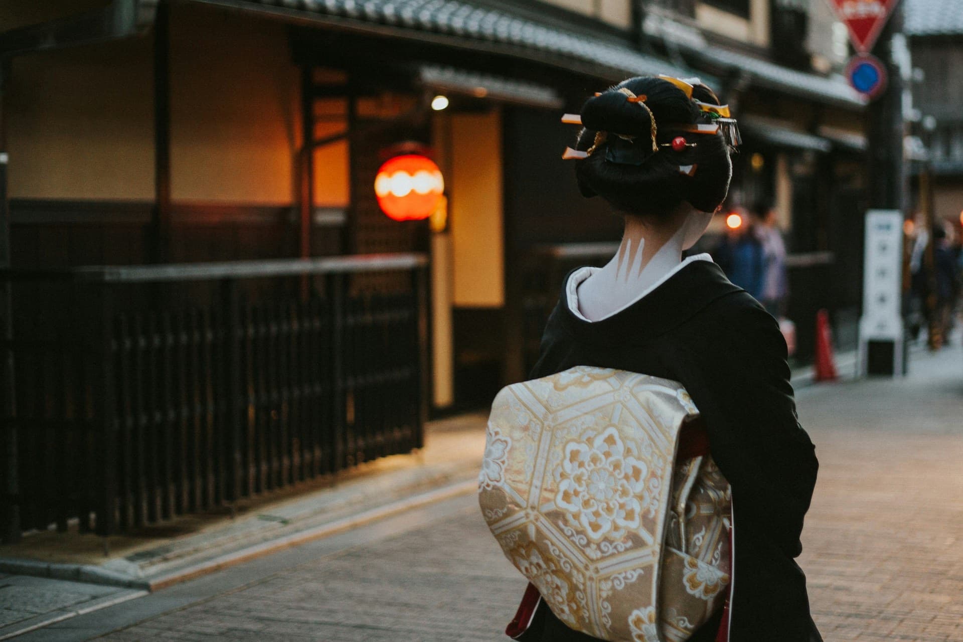 Woman in a kimono walking down a Japanese city sidewalk