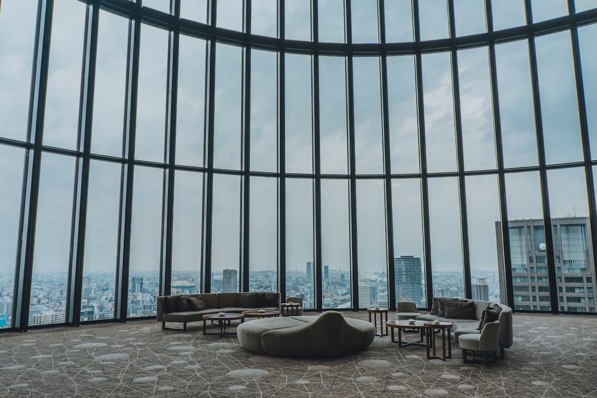 Osaka's low, wide skyline seen through the curved glass wall of a high-floor hotel lounge