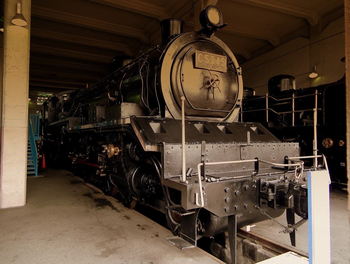 A black steam locomotive standing in the old Umekoji roundhouse