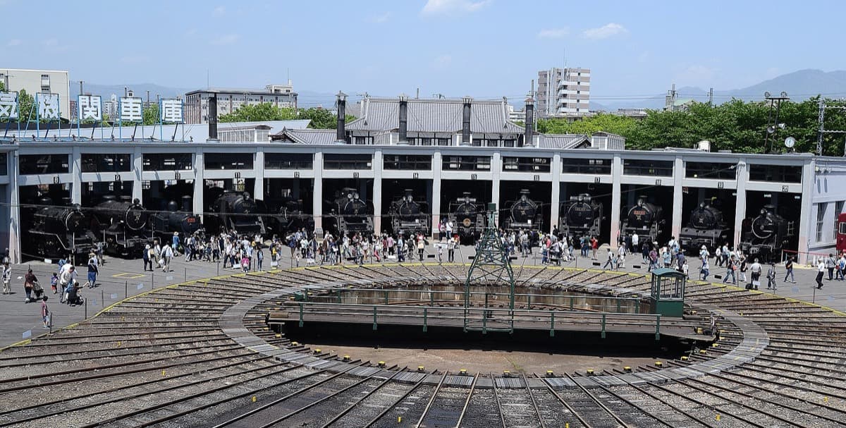 The semicircular roundhouse and turntable of the Kyoto Railway Museum with visitors watching