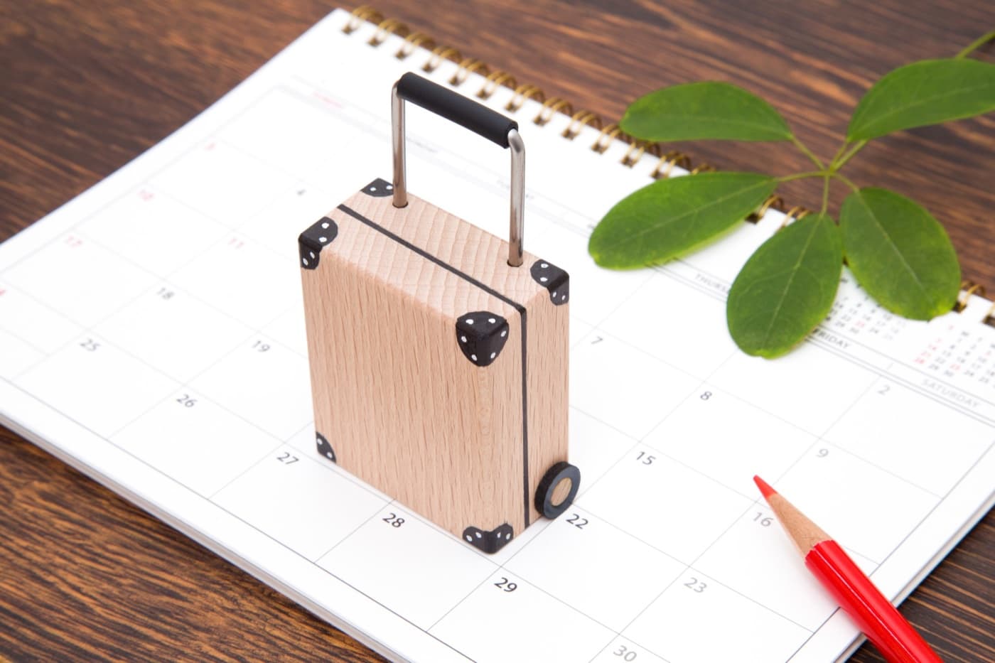 Ein Tischkalender mit einem kleinen Holzkoffer darauf, als Sinnbild für die Planung einer Japanreise rund um den Feiertagskalender 2027