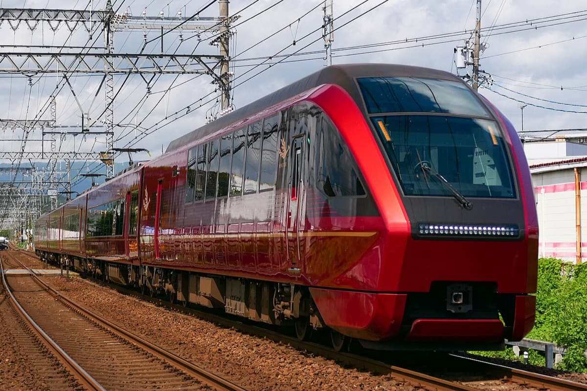 Kintetsu's red Hinotori express with a rounded glass front, running on a straight track under overhead wires
