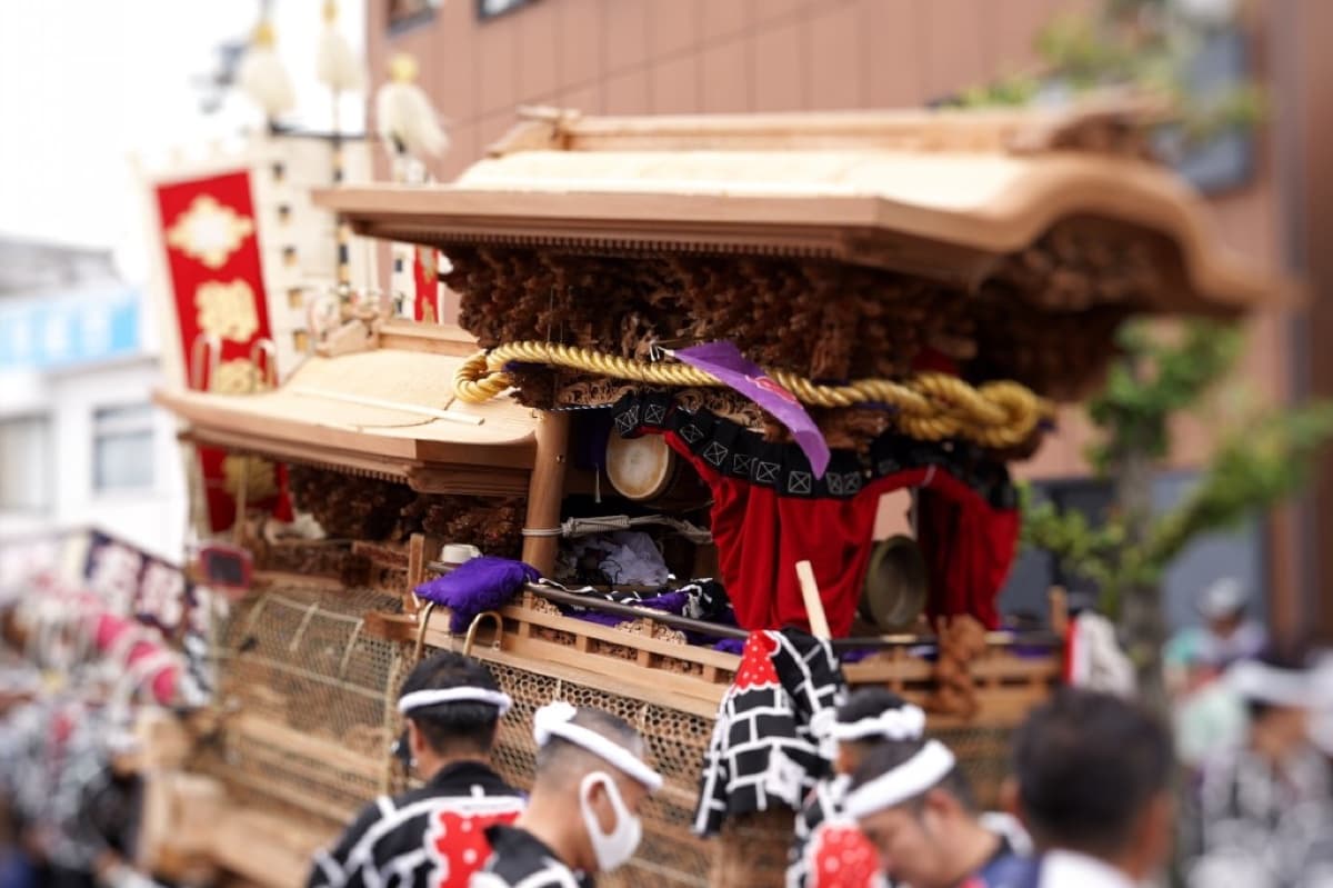 Close-up of an ornate Kishiwada danjiri float with carved wood, red drapery and festival pullers in happi coats