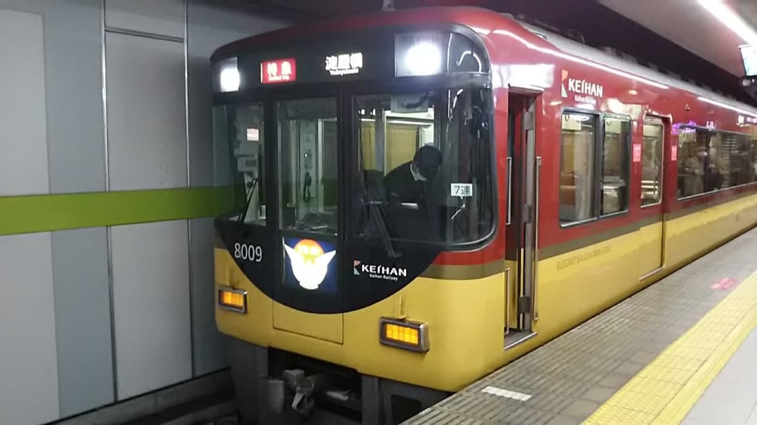 A red and yellow Keihan 8000 series limited express waiting at an underground platform bound for Yodoyabashi