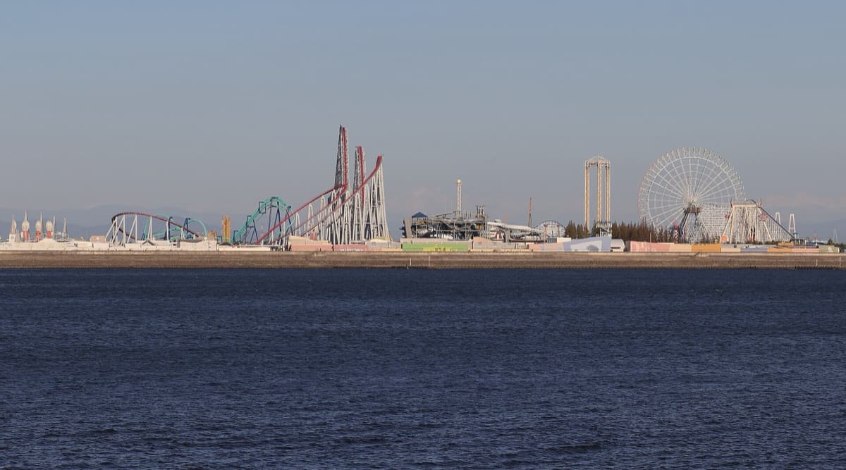 The roller coasters and Ferris wheel of Nagashima Spa Land seen across the river at dusk