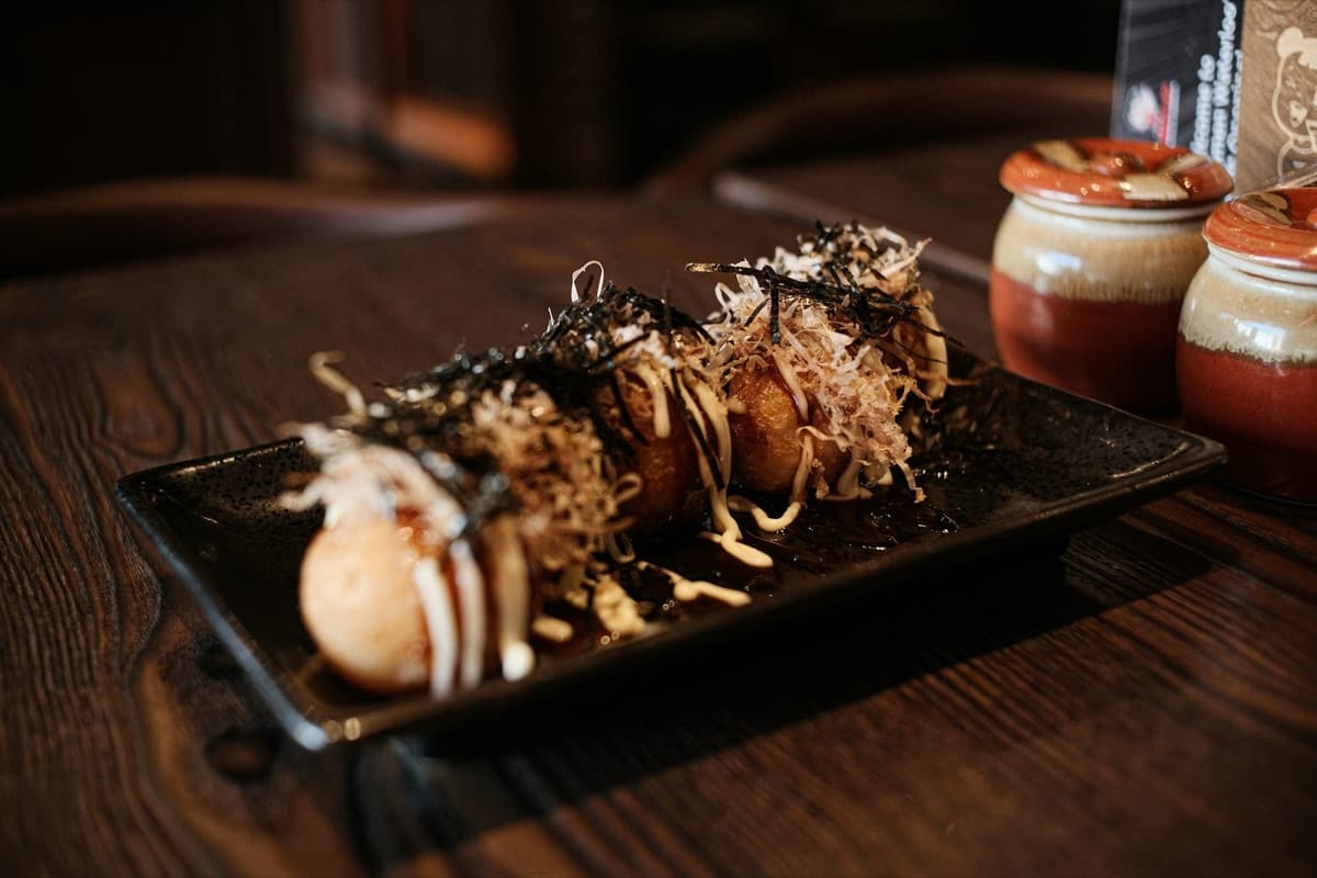 A plate of takoyaki topped with sauce, mayonnaise and bonito flakes