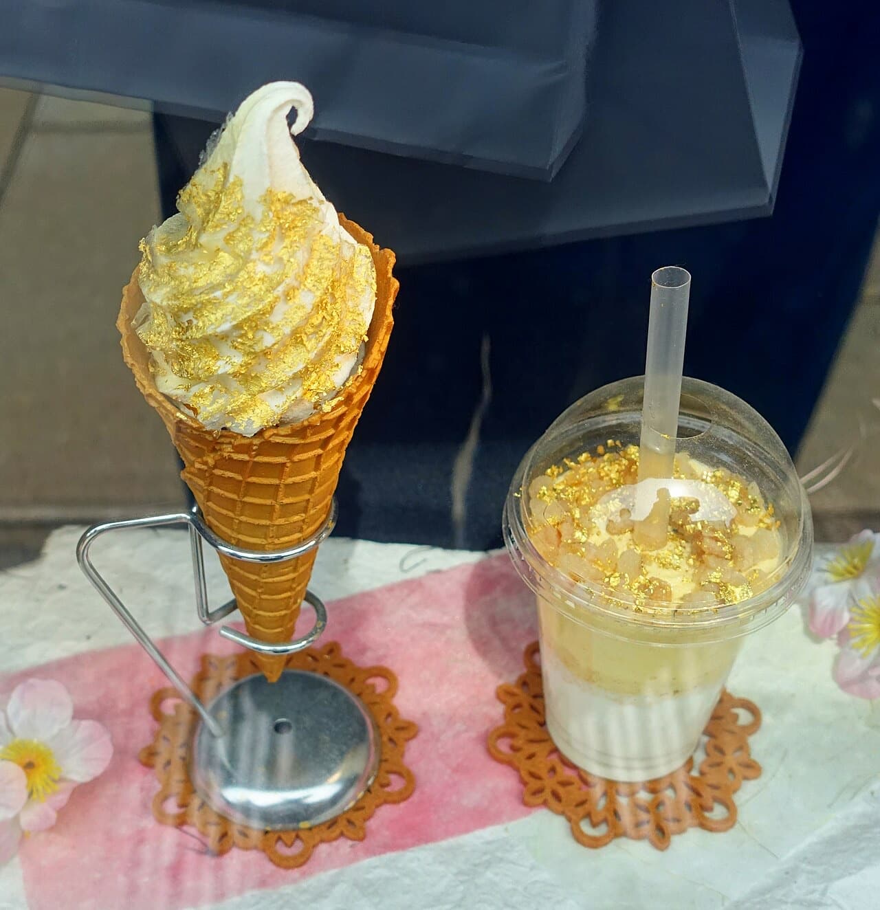 A soft-serve ice cream cone covered in a sheet of gold leaf
