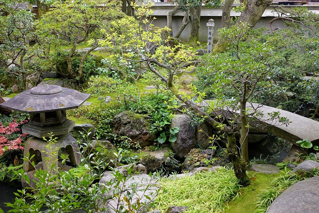 A small Japanese garden with a stone lantern, moss, pine and a stream at the Nomura samurai residence