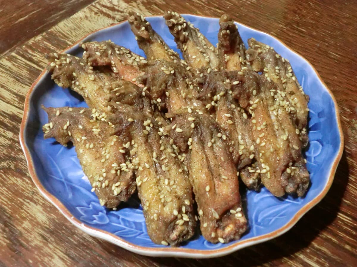A plate of peppery fried chicken wings sprinkled with sesame seeds