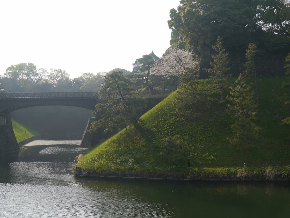A stone bridge over the green moat and grassy stone walls of the Imperial Palace