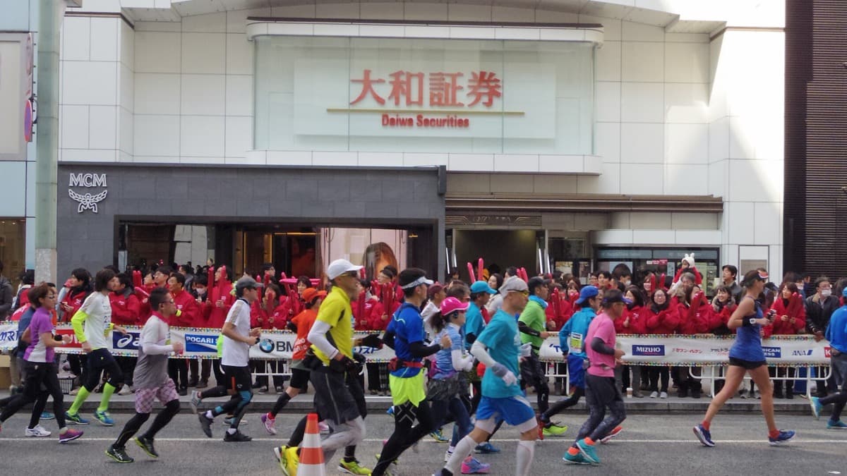 A cheering squad in red jackets lining the course in Ginza as marathon runners pass