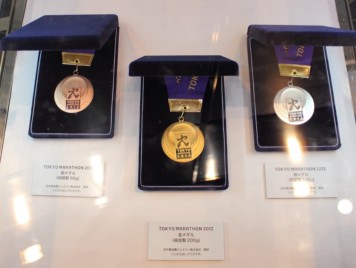 Three Tokyo Marathon finisher medals in open presentation boxes on display
