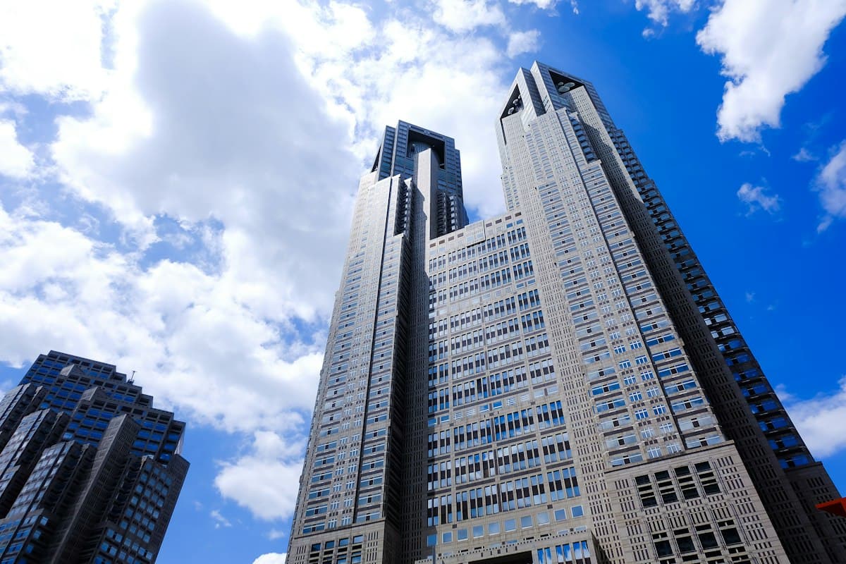 The twin towers of the Tokyo Metropolitan Government Building against a blue sky with clouds