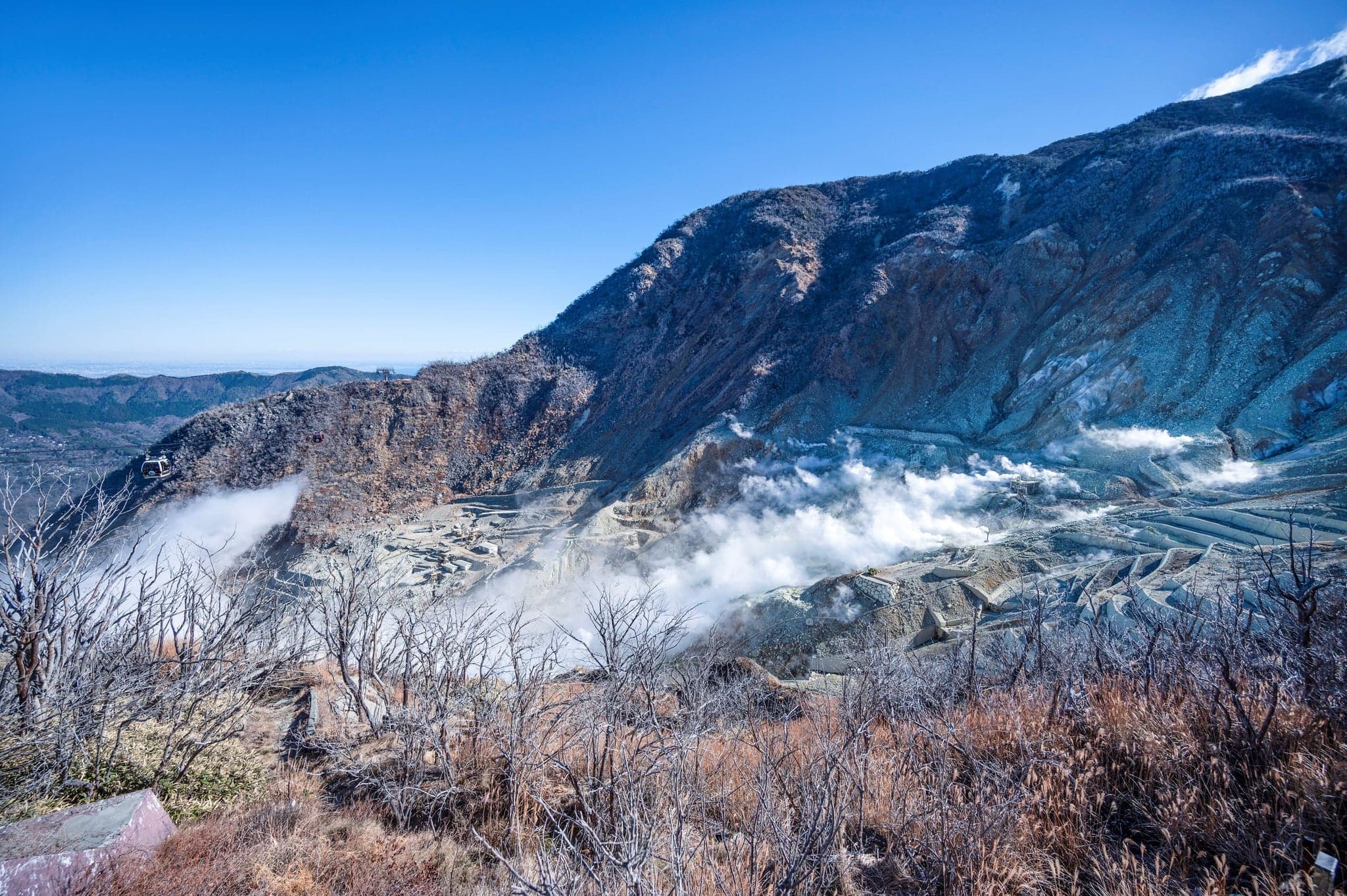 White volcanic steam rising from the bare slopes of Owakudani under a blue sky