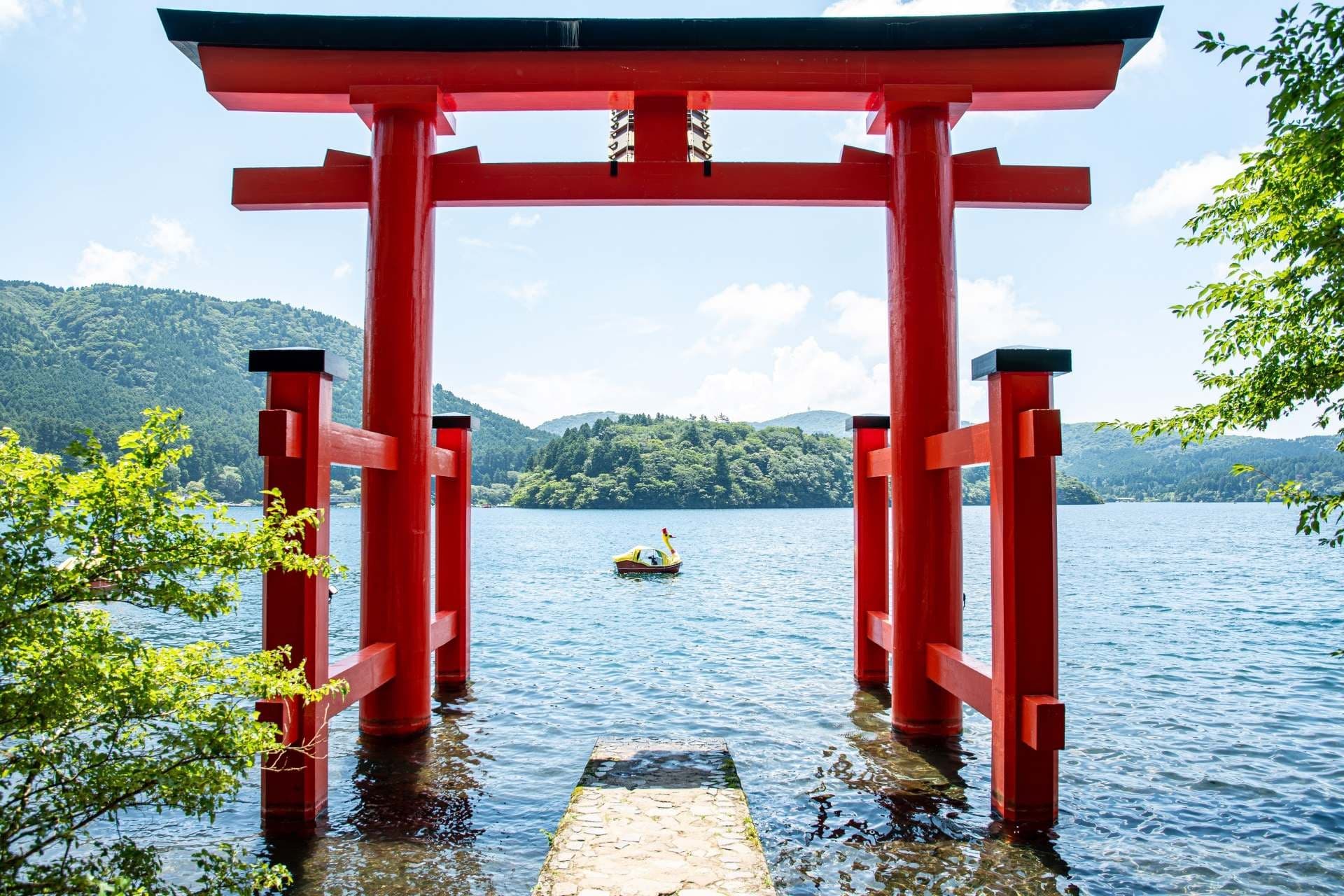 The red torii of Hakone Shrine standing in the clear water of Lake Ashi