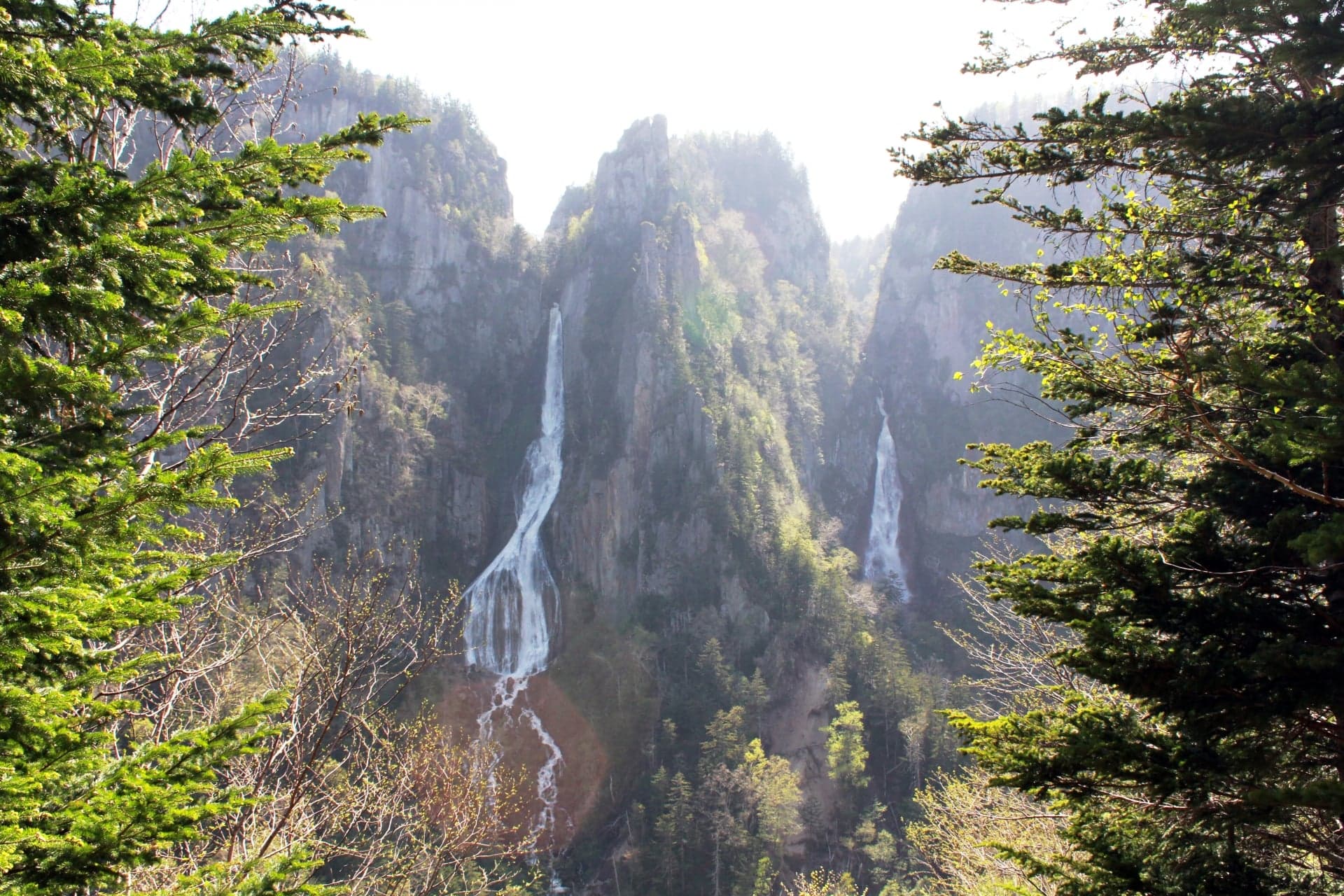 Ginga Falls dropping in white ribbons down a tall green cliff in Sounkyo gorge