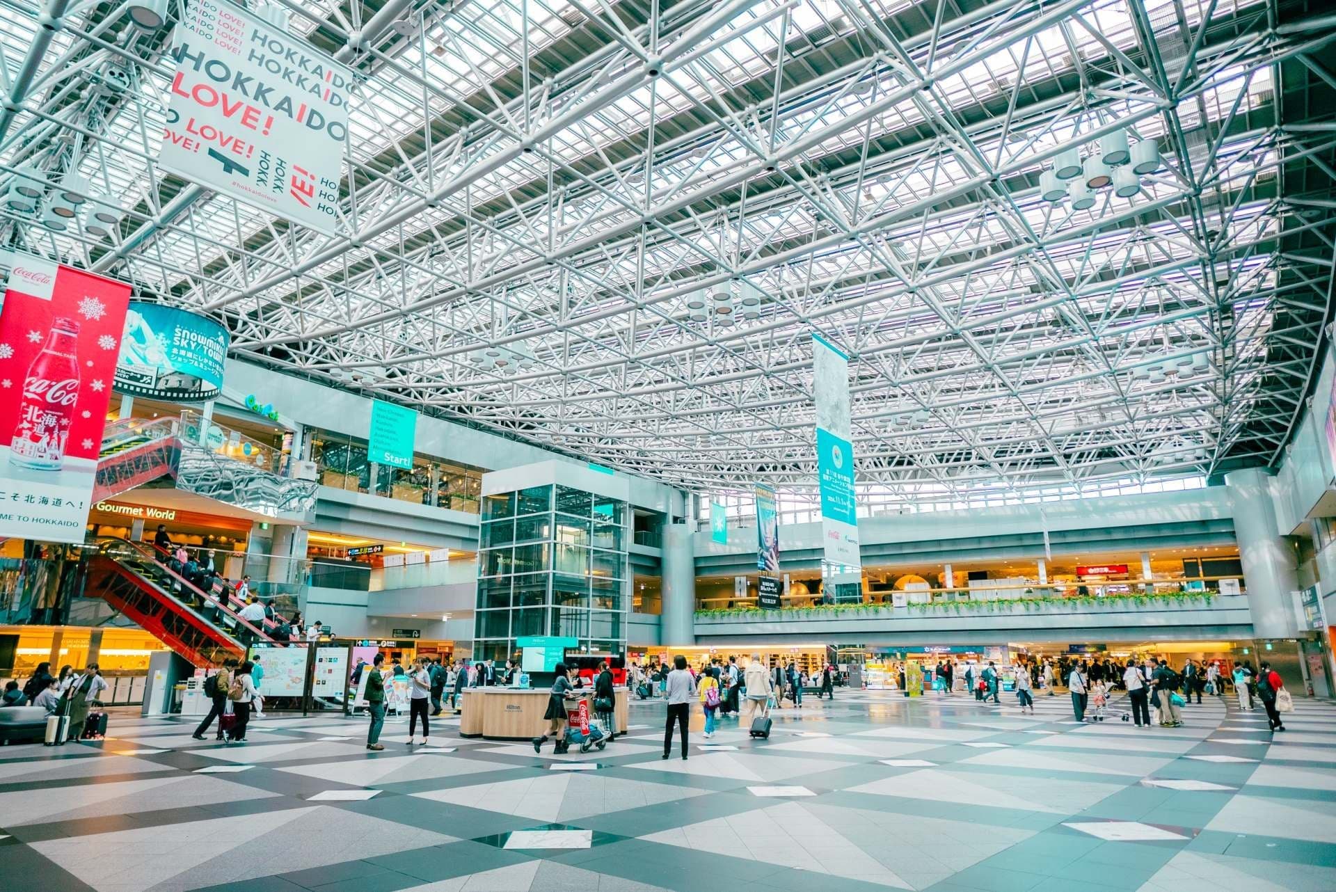 The bright domestic terminal hall at New Chitose Airport with shops and travelers