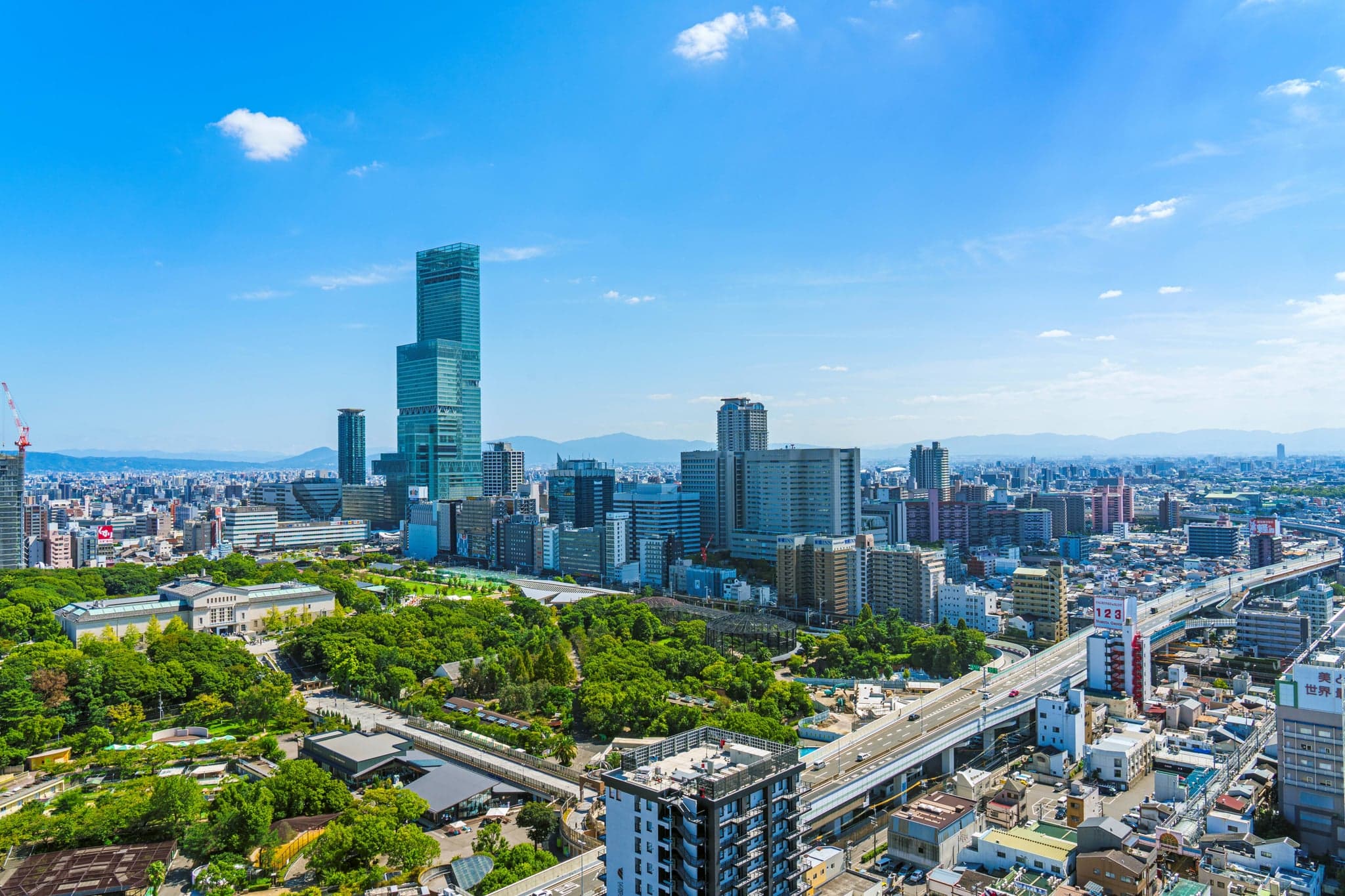 Vista aérea de las zonas verdes del parque Tennoji con la torre Abeno Harukas y la ciudad detrás