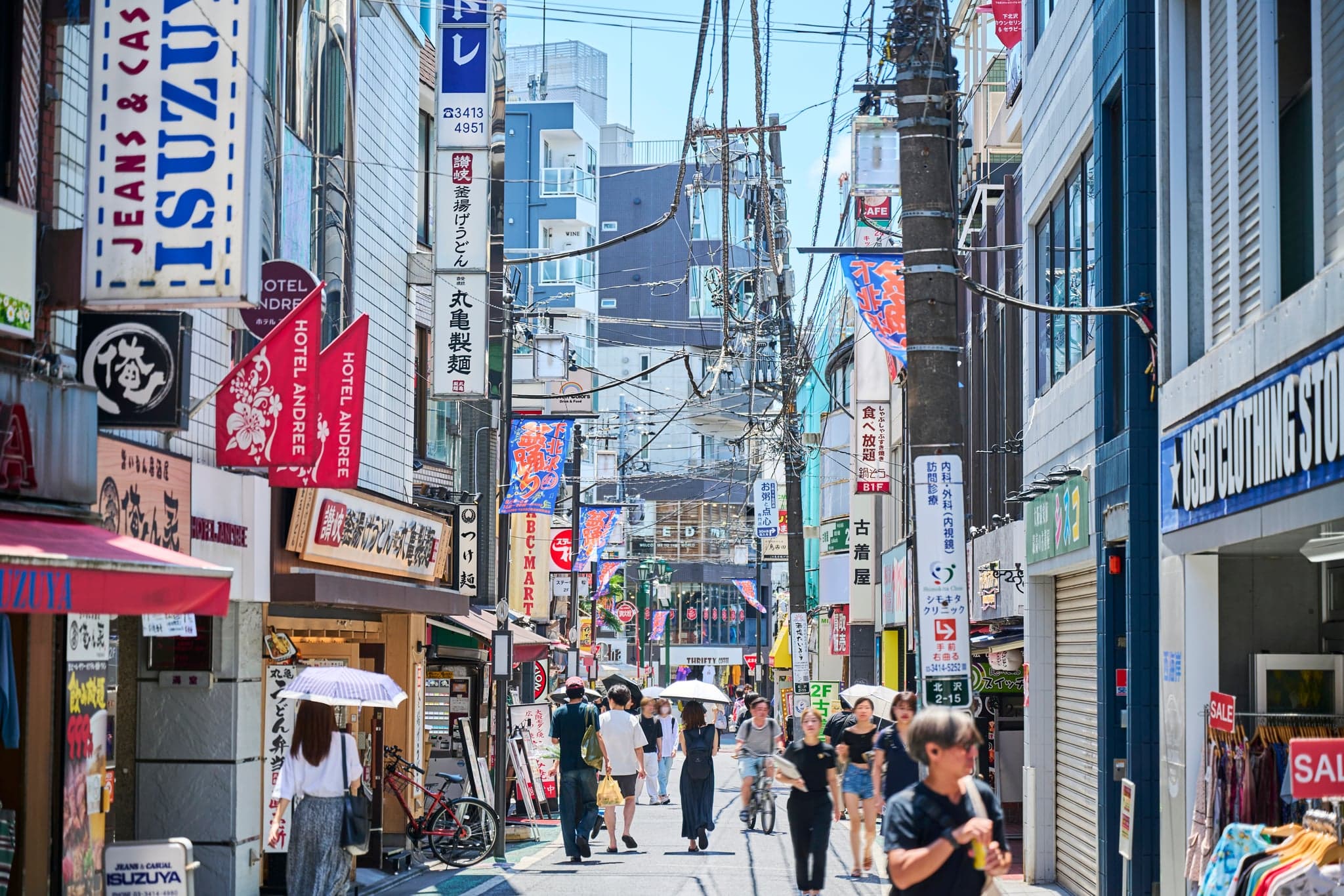 A busy shopping street in Shimokitazawa with shop signs and pedestrians