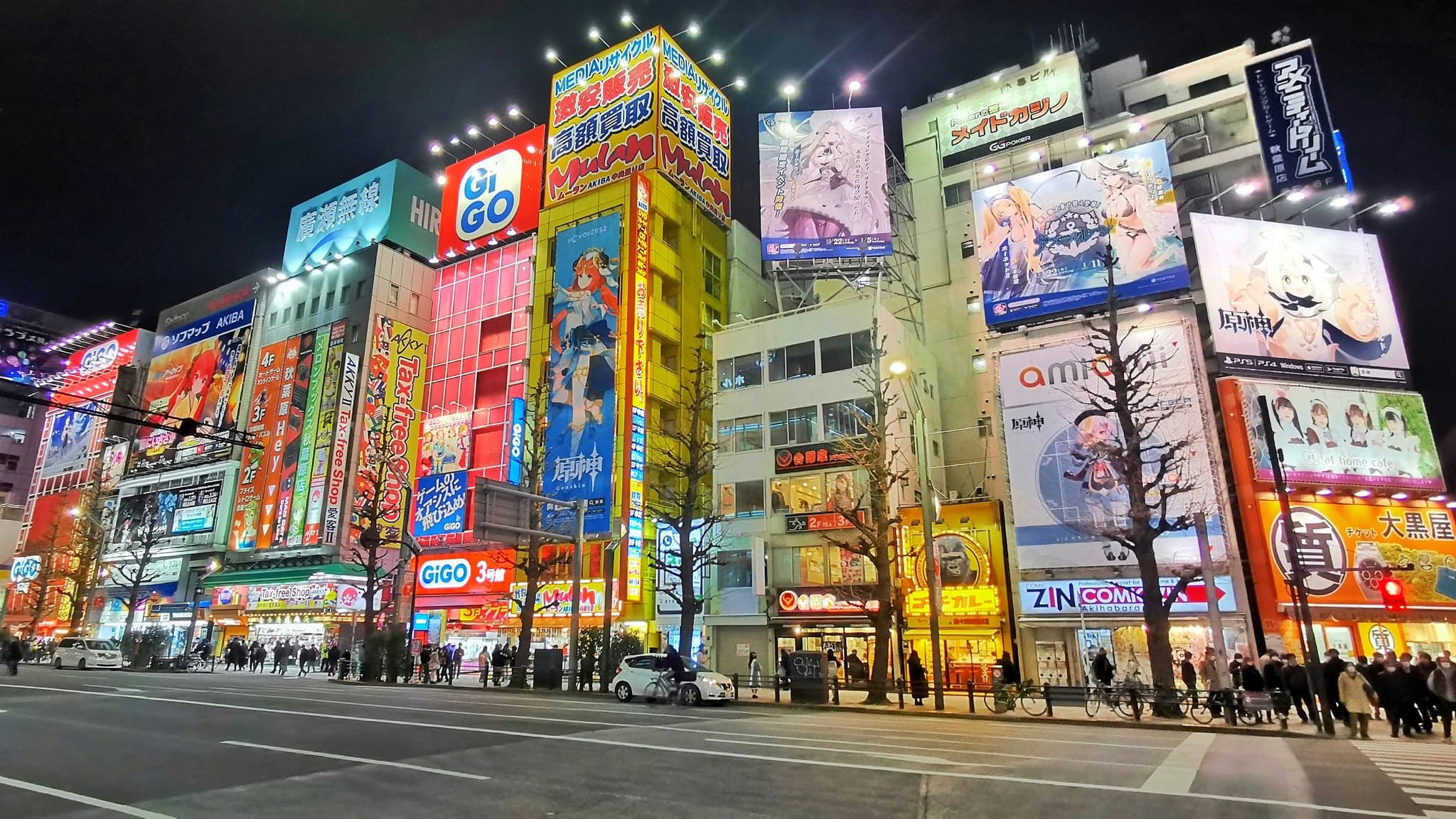 Akihabara's main street at night lined with buildings covered in bright anime billboards