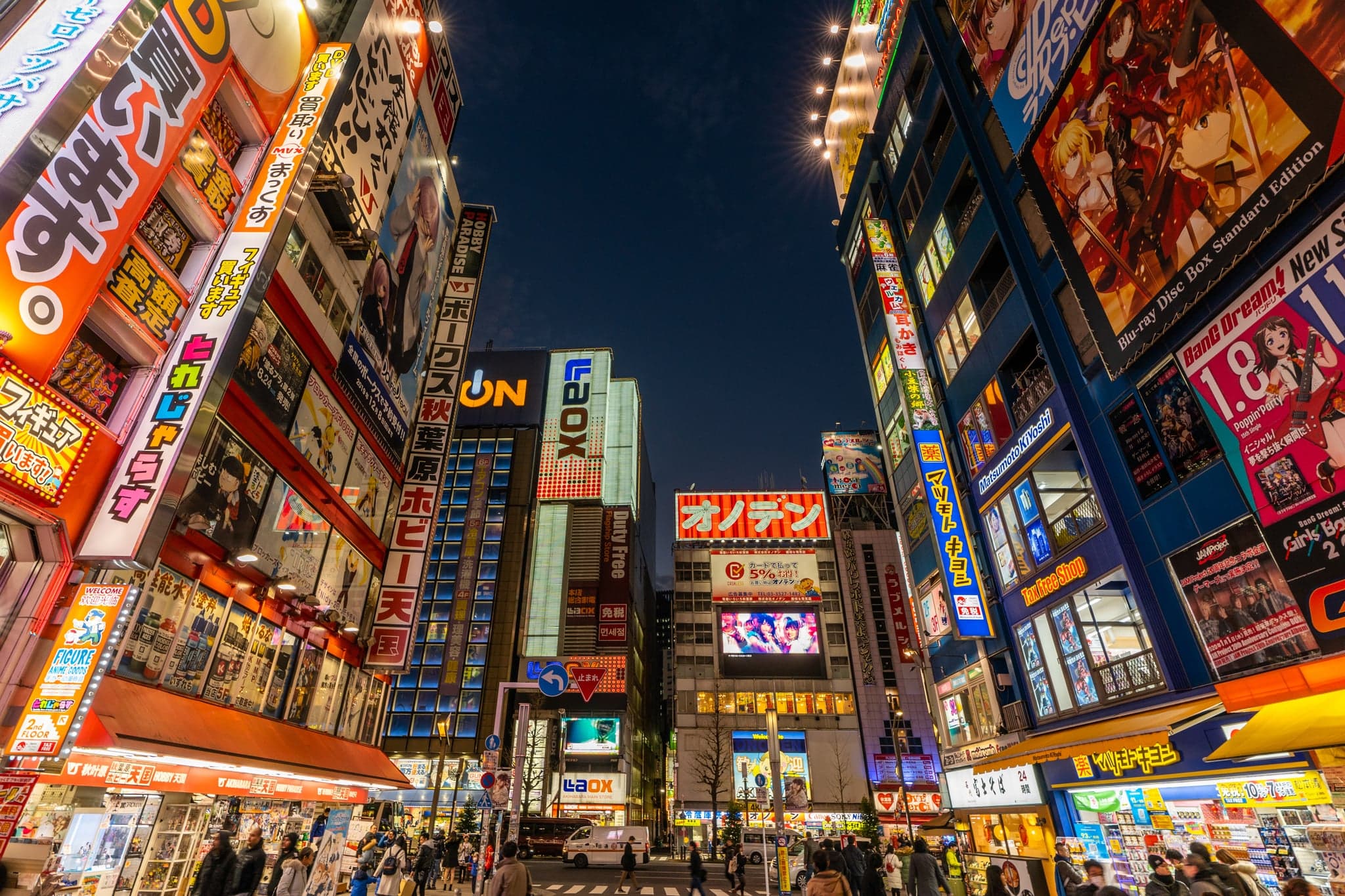 Looking up at the crowded neon and anime signs on the buildings of an Akihabara street