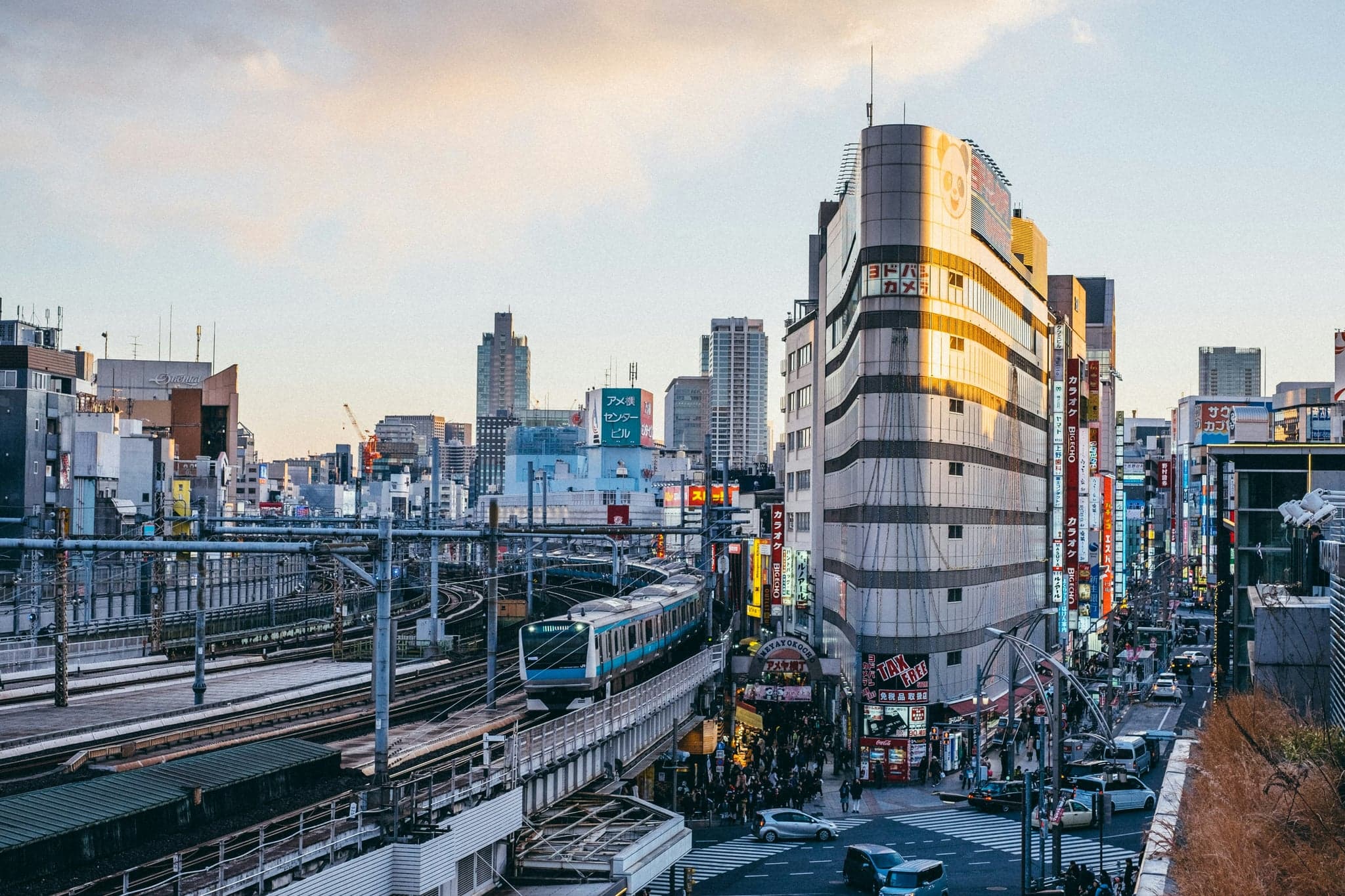 JR commuter trains running along the tracks past Ueno, with city buildings on either side